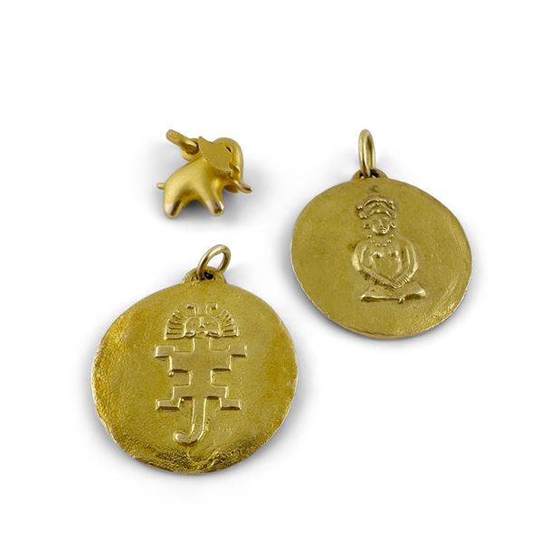Due medaglie con segno zodiacale e un piccolo ciondolo con elefante in oro 18kt.